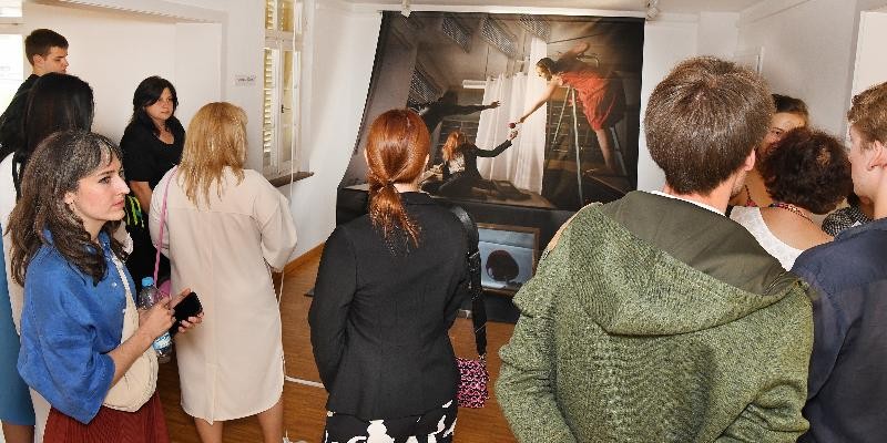 Mehrere Besucher betrachten Kunstwerk bei einer Vernissage