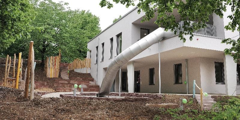 Außenansicht eines modernen Gebäudes mit Rutsche und Garten