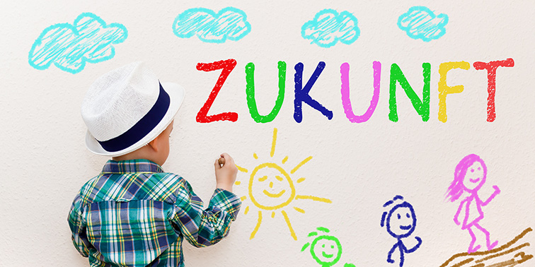 Ein Kind malt bunte Zeichnungen und das Wort „Zukunft“ groß an eine Wand.