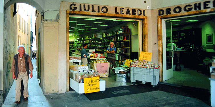 Fußgänger gehen in Voghera durch Aracaden, rechts: ein Drogeriegeschäft mit großer Beschriftung"GIULIO LEARDI"