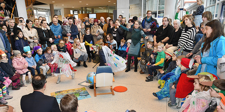 Kinder in Kostümen bei einer Aufführung, umringt von Eltern beim Tag der offenen Tür.