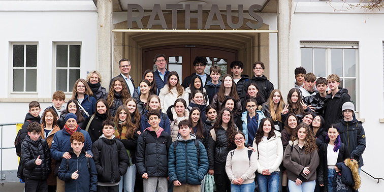 Eine große Schülergrippe steht vor dem Eingang eines Rathauses und posiert für ein gemeinsames Foto.