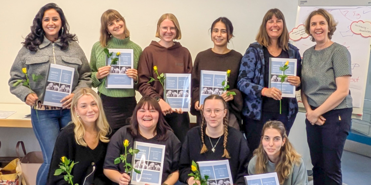 Eine Gruppe lächelnder Frauen hält Zertifikate und gelbe Rosen in der Hand