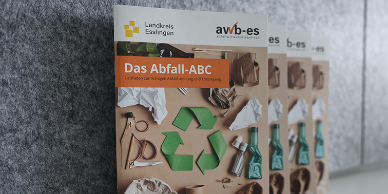 Mehrere Exemplare einer Broschüre „Das Abfall‑ABC“ liegen nebeneinander auf grauem Untergrund.