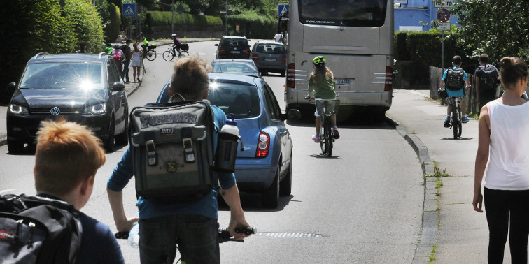 Straßenverkehr mit Radfahrern, Autos, Bus – und Passanten auf dem Gehweg