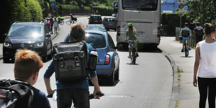 Verkehrsplanung & Mobilität Straßenverkehr mit Radfahrern, Autos, Bus – und Passanten auf dem Gehweg