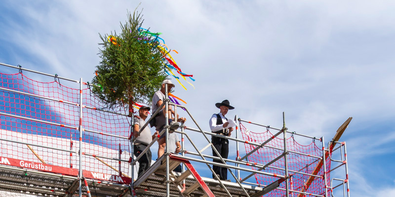 Richtbaum wird beim Richtfest der neuen Energiezentrale auf dem Gerüst aufgestellt.