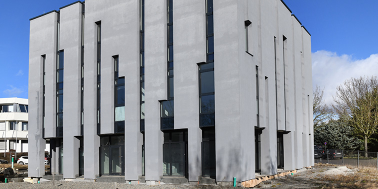 Ein graues Gebäude mit großen länglichen Fenstern