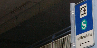 Park+Ride-Verkehrsschild mit grün-weißem S-Bahn-Logo vor Eingang eines P+R-Parkhauses