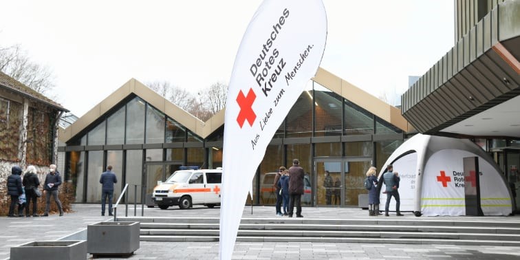 Auto, Fahne, Zelt des Deutschen Roten Kreuzes und Personen vor der Filderhalle 