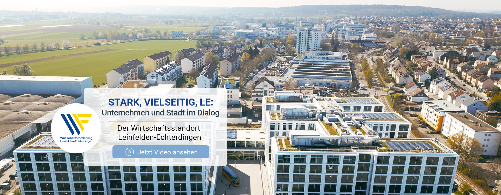 Industriegebäude mit großer Glasfassade und grünen Bäumen davor