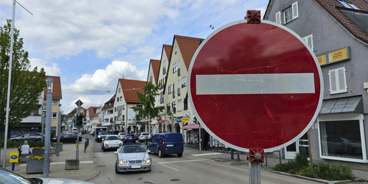 Rotes Einbahnstraßenschild mit Fahrzeugen auf Straße