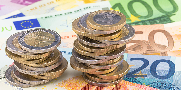 Eine Ansammlung von Euro-Münzen vor einem Hintergrund aus Euro-Banknoten.