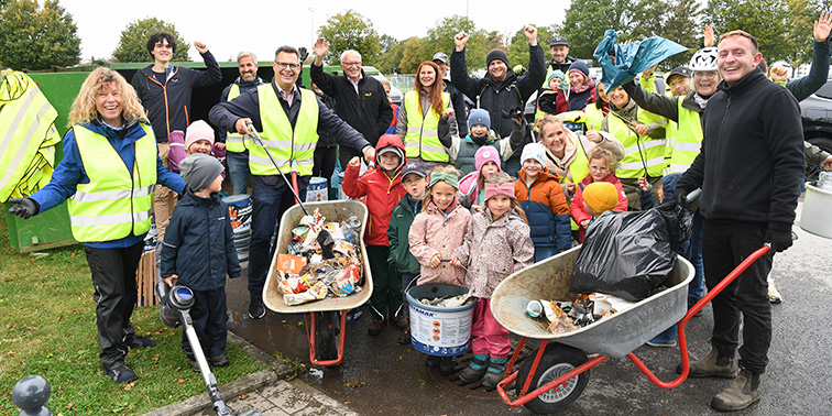 Menschen in gelben Sicherheitswesten arbeiten zusammen, um Müll mit Schaufeln und Säcken zu beseitigen.