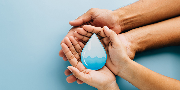 Mehrere Hände halten gemeinsam einen stilisierten blauen Wassertropfen – Symbol für Wasser und Zusammenhalt