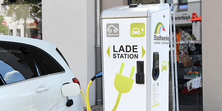 Ein weißer Pkw wird an einer Elektroladestation aufgeladen.