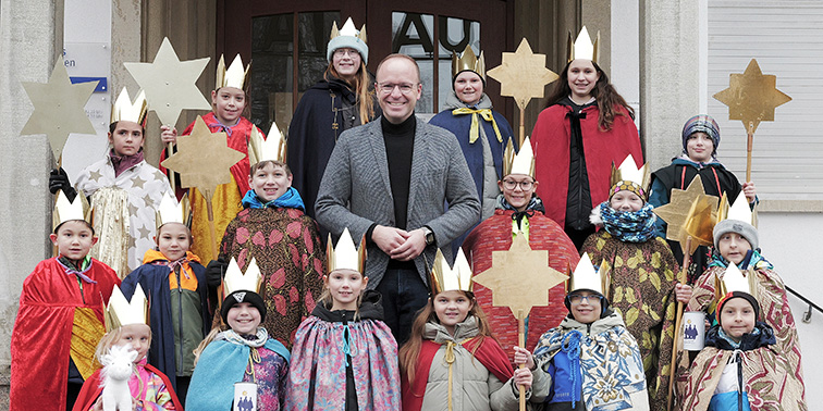 Eine Gruppe von Kindern in Kostümen hält Sterne in den Händen und lächelt fröhlich in die Kamera.