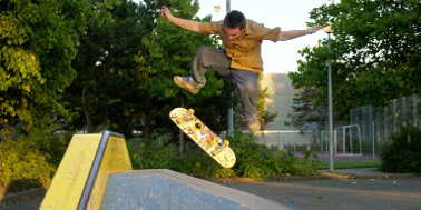 Skater springt mit Skateboard über eine Rampe