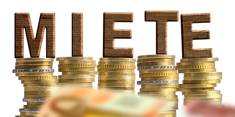 „Das Wort ‚Miete‘ auf Stapeln von Euro-Münzen, davor Euro-Geldscheine