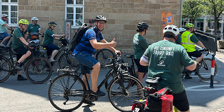 Radfahrer (unter anderem mit Bürgermeister Dr. Kalbfell) bei einer Sternfahrt mit Halt vor einem Gebäude.
