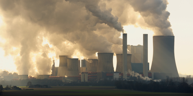 Großes Kohlekraftwerk mit vielen Kühltürmen und Schornsteinen, aus denen dichte Rauch- und Dampfwolken in den Himmel steigen