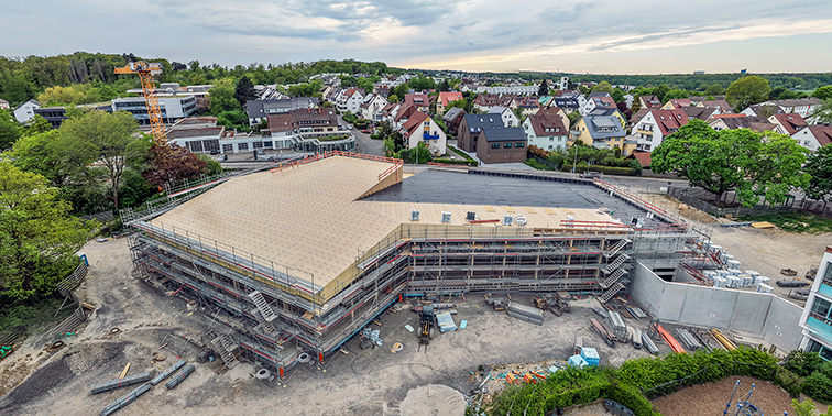 Luftaufnahme eines im Bau befindlichen Gebäudes, das Baustellenmaterialien zeigt.