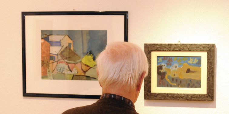 Senior betrachtet Bilder in einer Kunstgalerie